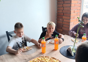 Uczniowie kl. IVc jedzą pizzę.