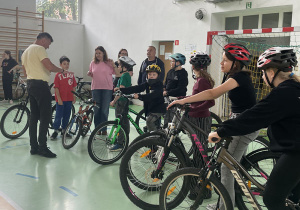 Przedstawiciel Mobilnego Miasteczka Ruchu Drogowego z Wojewódzkiego Ośrodka Ruchu Drogowego w Sieradza omawia trasę przejazdu rowerami podczas egzaminu praktycznego na kartę rowerową.